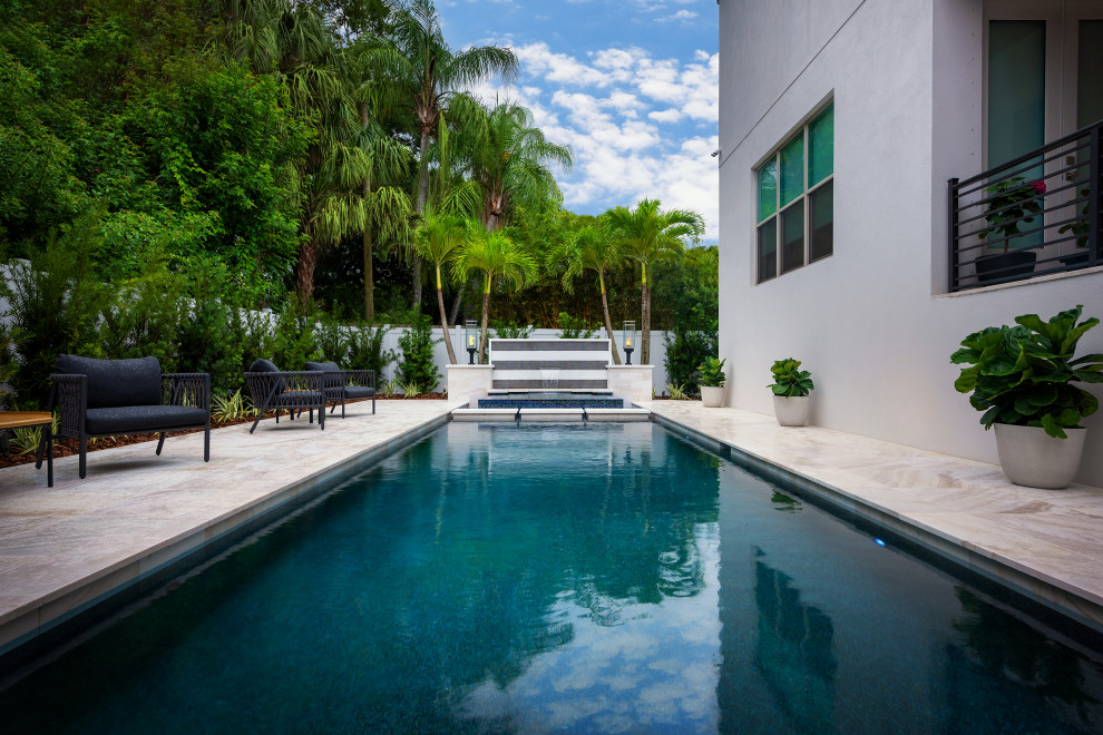 Foto di una piscina a sfioro infinito design personalizzata di medie dimensioni e dietro casa con paesaggistica bordo piscina e piastrelle