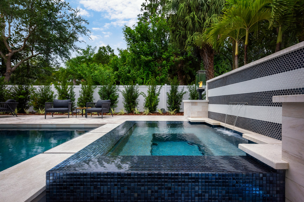 Imagen de piscina infinita contemporánea de tamaño medio a medida en patio trasero con paisajismo de piscina y suelo de baldosas