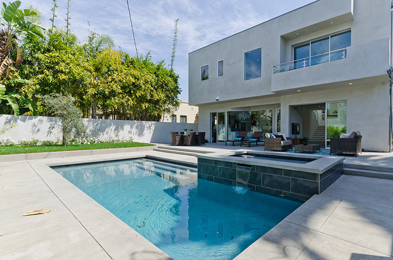 Ejemplo de piscinas y jacuzzis alargados minimalistas grandes rectangulares en patio trasero con adoquines de hormigón