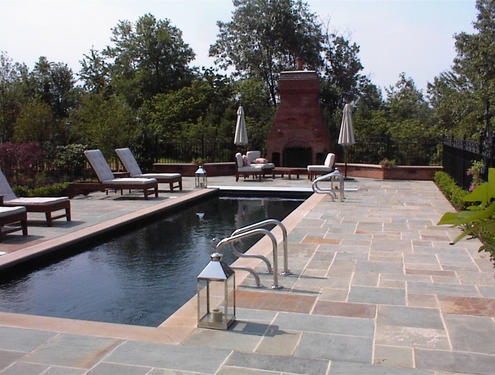 Esempio di una grande piscina monocorsia design rettangolare dietro casa con pavimentazioni in pietra naturale e una vasca idromassaggio