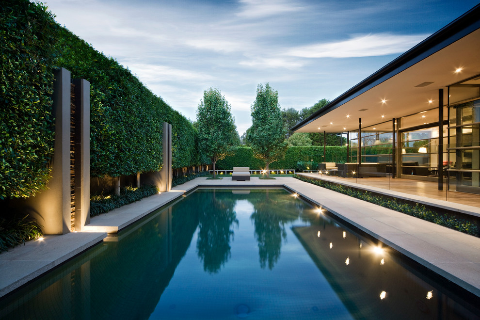 На фото: большой прямоугольный бассейн на заднем дворе в стиле модернизм с покрытием из декоративного бетона