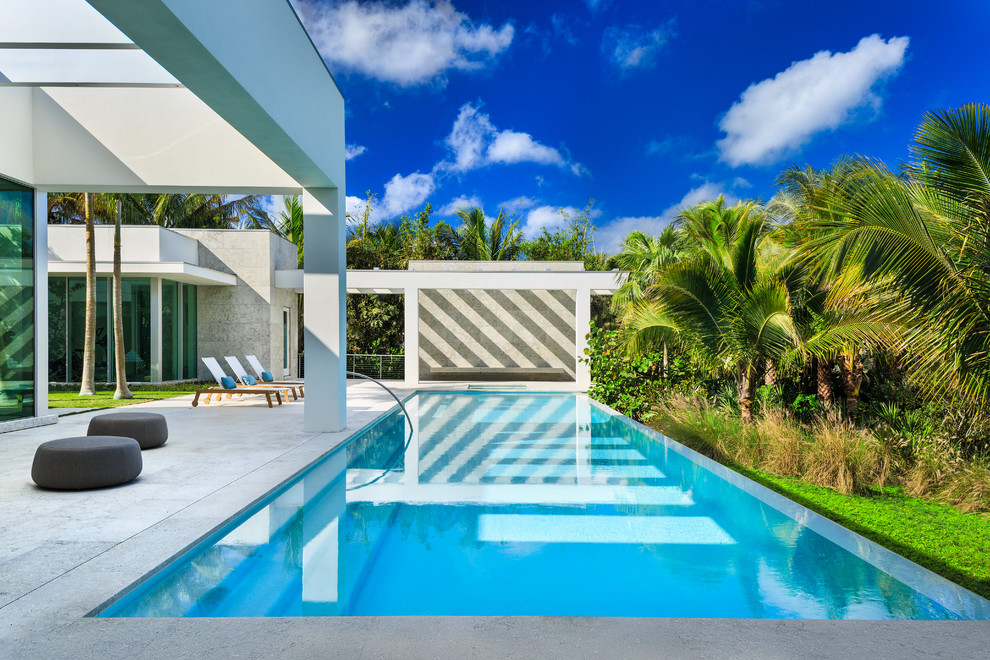 Immagine di un'ampia piscina monocorsia minimalista rettangolare dietro casa con lastre di cemento
