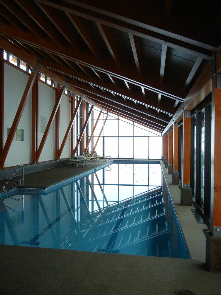 Foto di una grande piscina coperta monocorsia minimalista a "L" con lastre di cemento