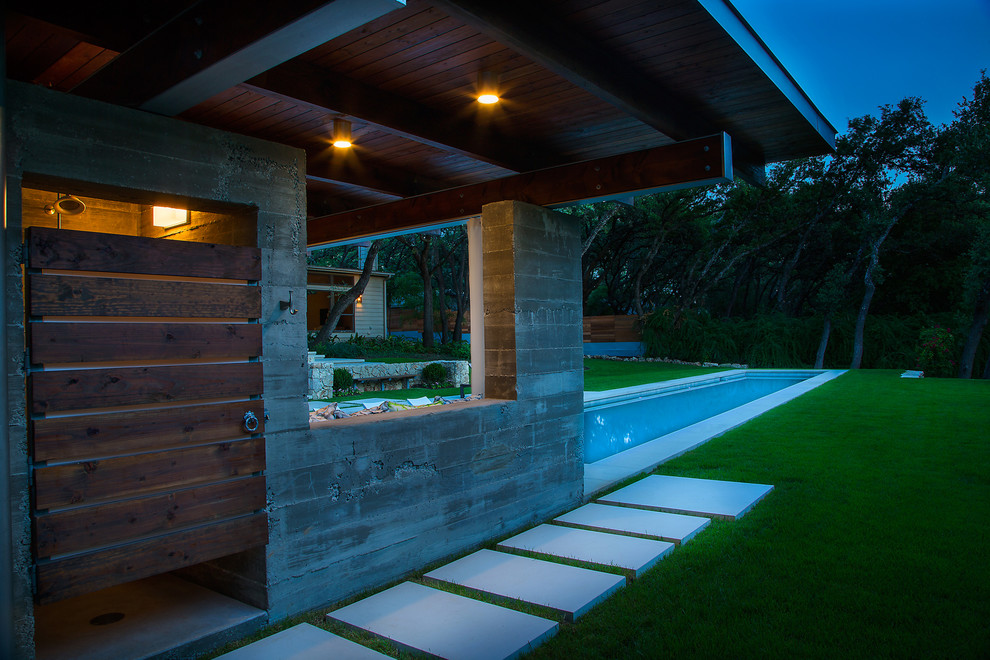 Cette image montre une grande piscine arrière minimaliste rectangle avec des pavés en pierre naturelle.
