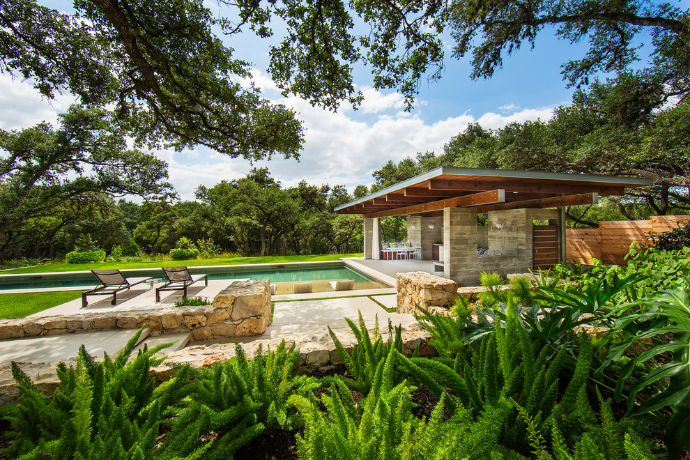 Modelo de casa de la piscina y piscina alargada moderna grande rectangular en patio trasero con adoquines de piedra natural