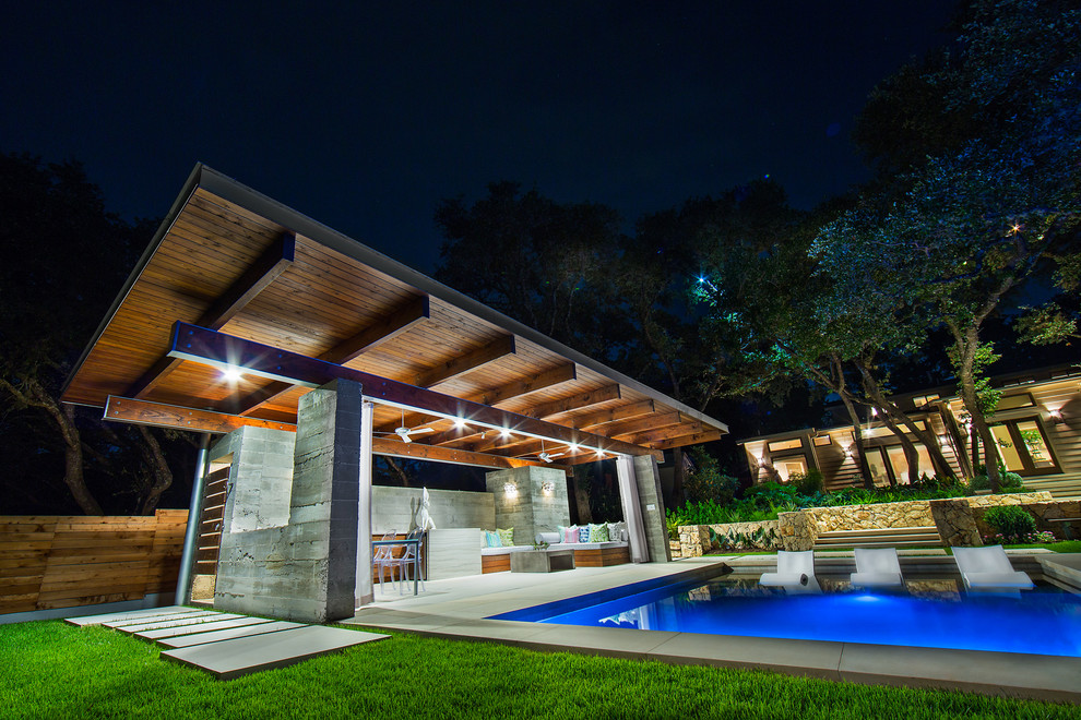 Pool house - large modern backyard stone and rectangular lap pool house idea in Austin