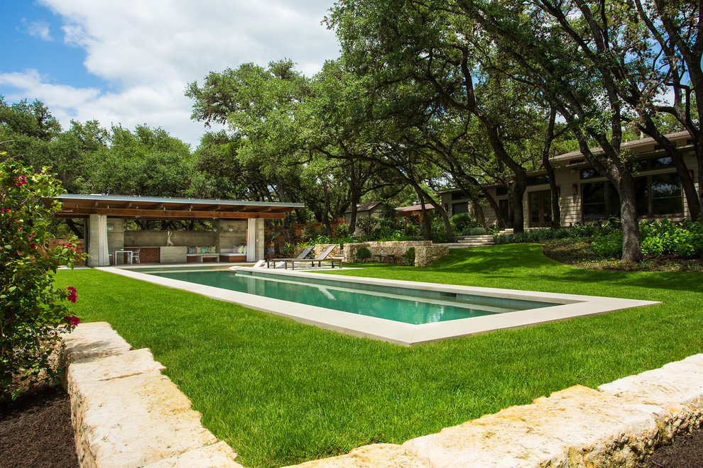 Ejemplo de casa de la piscina y piscina alargada moderna grande rectangular en patio trasero con adoquines de piedra natural