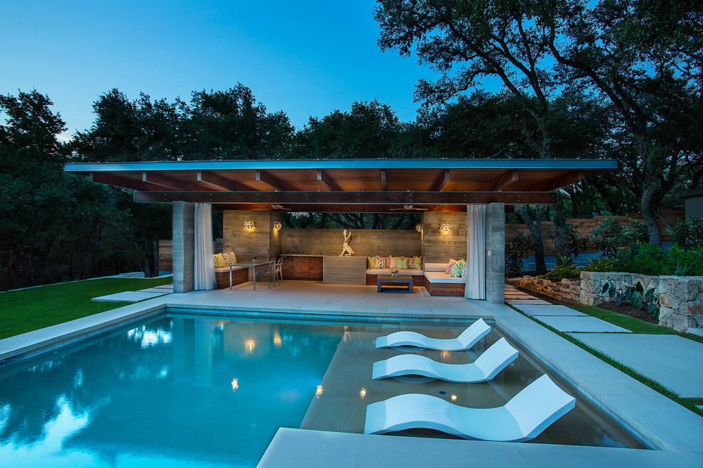 Ispirazione per una grande piscina monocorsia moderna rettangolare dietro casa con una dépendance a bordo piscina e pavimentazioni in pietra naturale