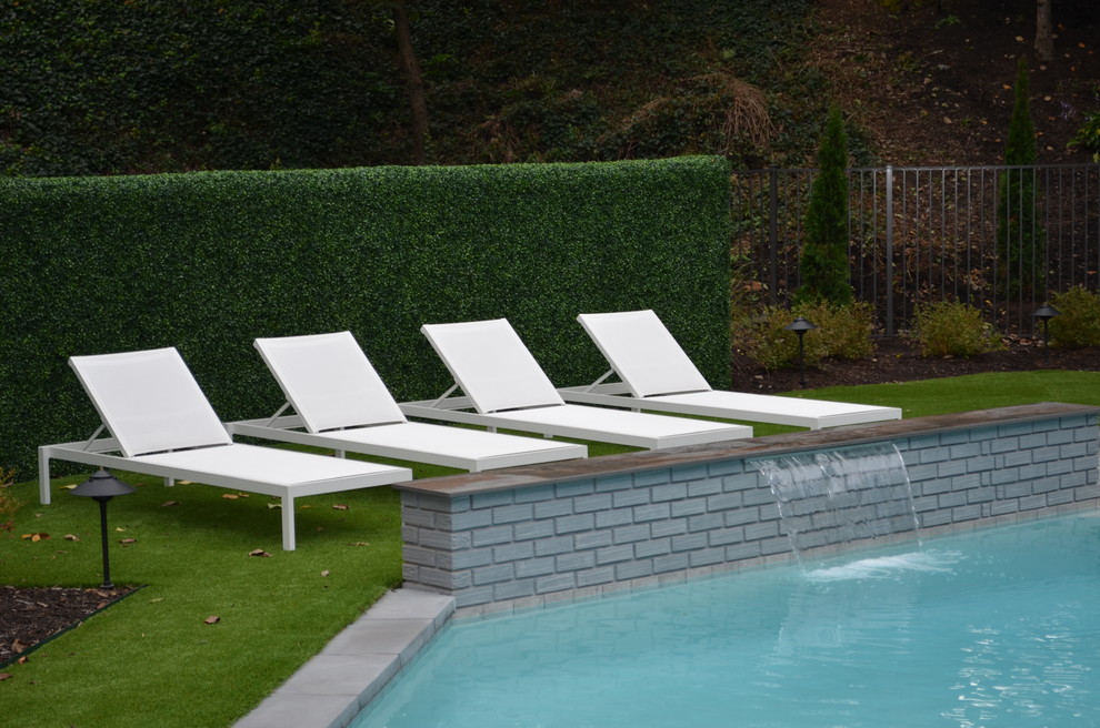 Ejemplo de piscina con fuente alargada minimalista de tamaño medio a medida en patio trasero con adoquines de hormigón