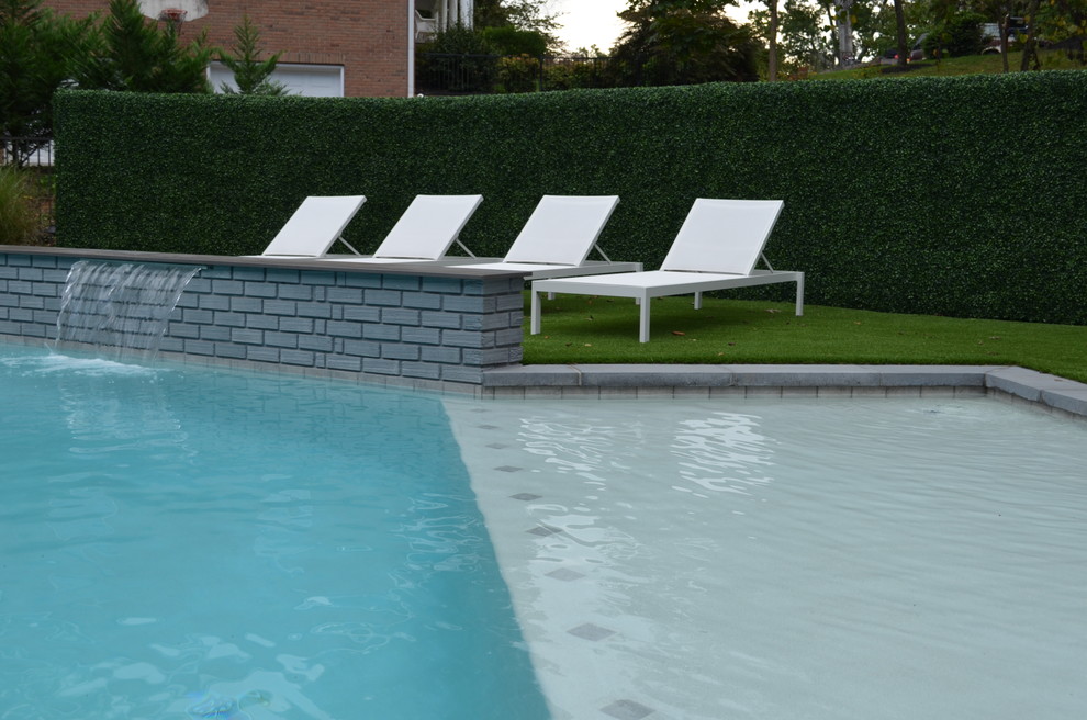 Ejemplo de piscina con fuente alargada minimalista de tamaño medio a medida en patio trasero con adoquines de hormigón