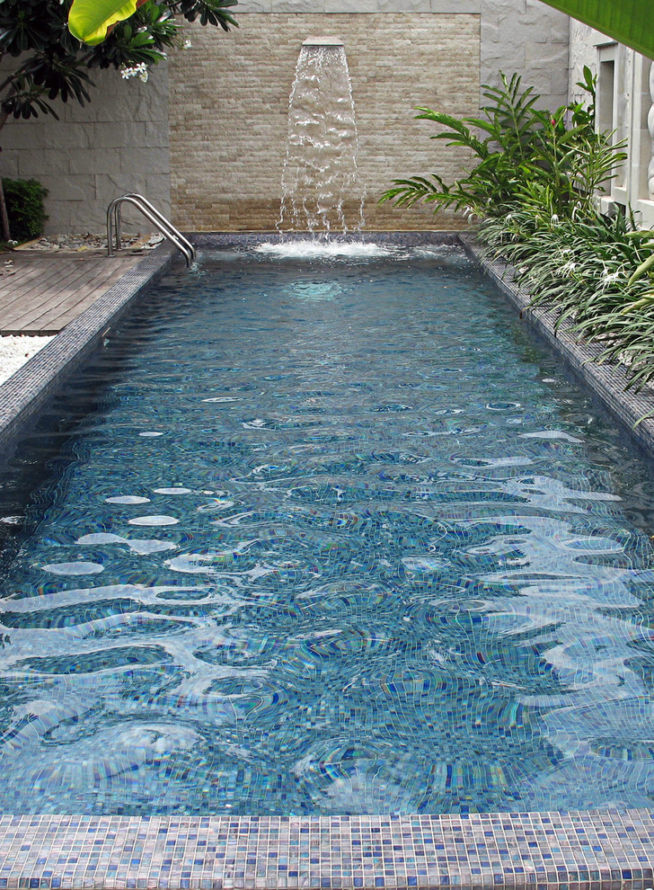 Diseño de piscina con fuente elevada minimalista de tamaño medio rectangular en patio trasero con gravilla