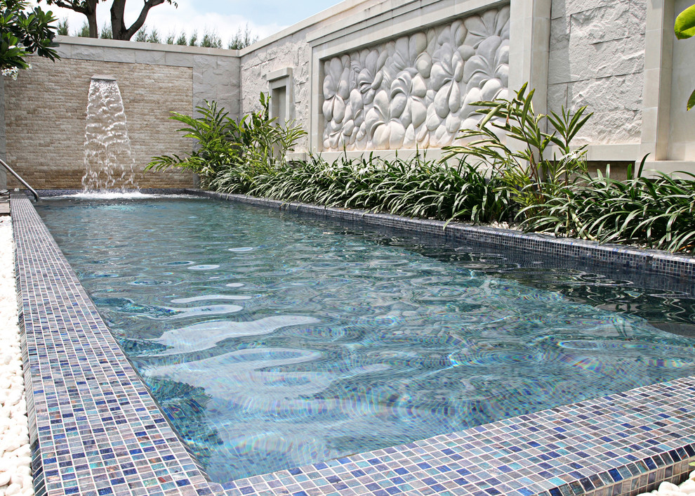 Imagen de piscina con fuente elevada moderna de tamaño medio rectangular en patio trasero con gravilla