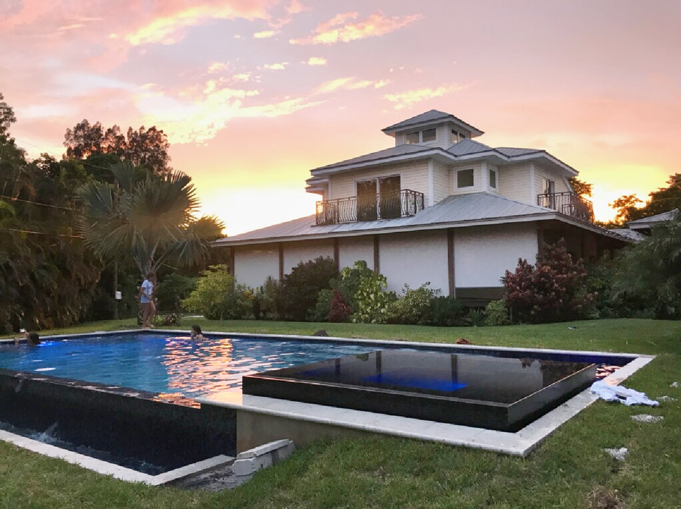 Ispirazione per una grande piscina moderna rettangolare dietro casa con una vasca idromassaggio
