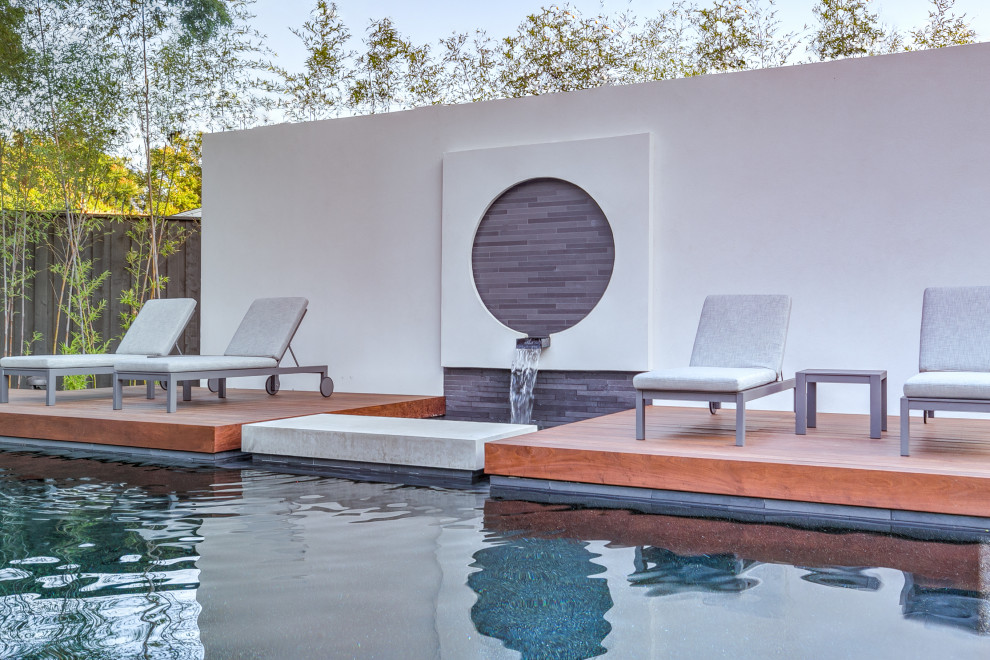 Идея дизайна: прямоугольный бассейн на заднем дворе в современном стиле с фонтаном и настилом