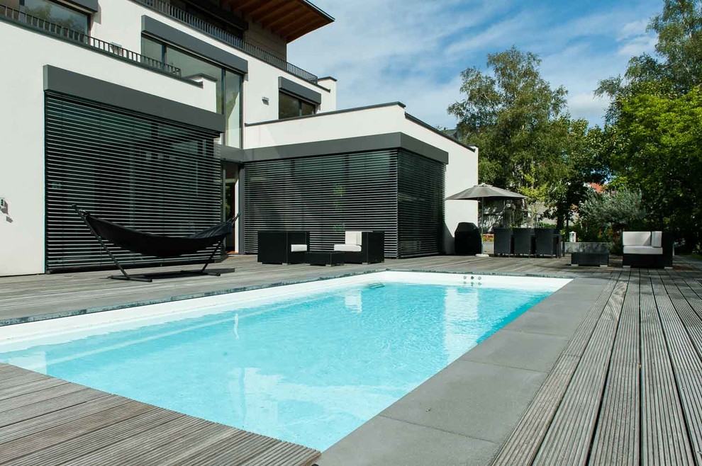 Imagen de piscina alargada actual de tamaño medio rectangular en patio trasero con entablado