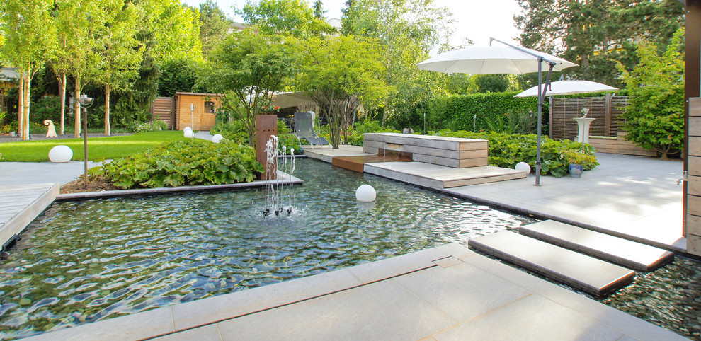 Idéer för funkis anpassad pooler på baksidan av huset, med en fontän och naturstensplattor