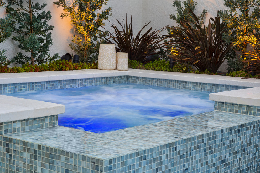 Esempio di una piccola piscina minimal rettangolare dietro casa con una vasca idromassaggio e piastrelle