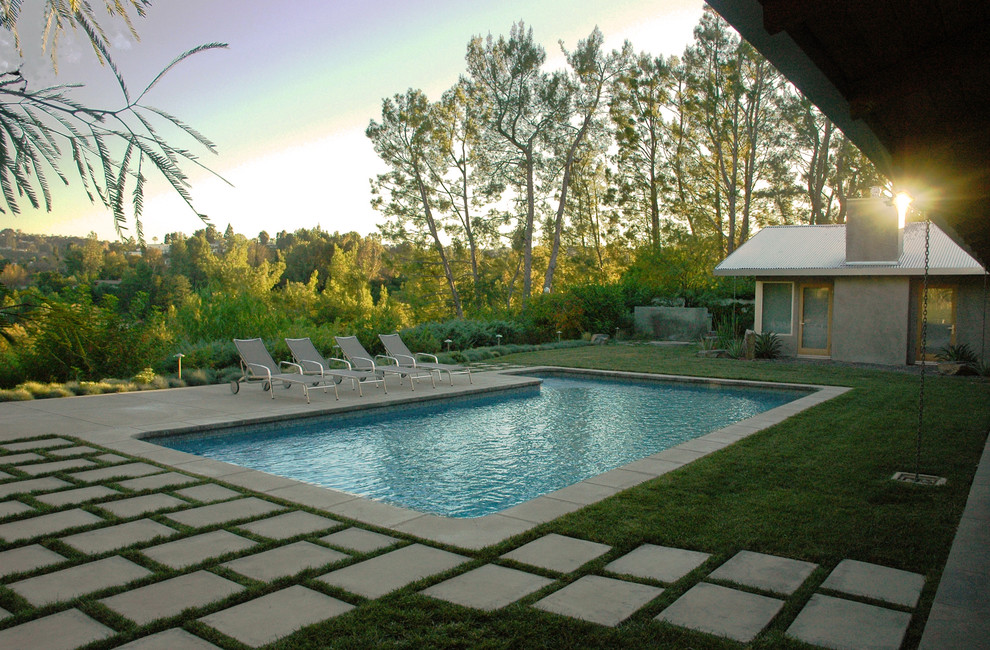 Diseño de piscina contemporánea grande en forma de L en patio trasero con adoquines de hormigón
