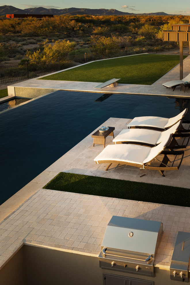 Ispirazione per una grande piscina design dietro casa con pavimentazioni in pietra naturale