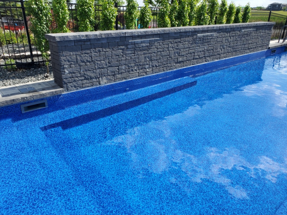 Ejemplo de piscina moderna de tamaño medio rectangular en patio trasero con adoquines de ladrillo