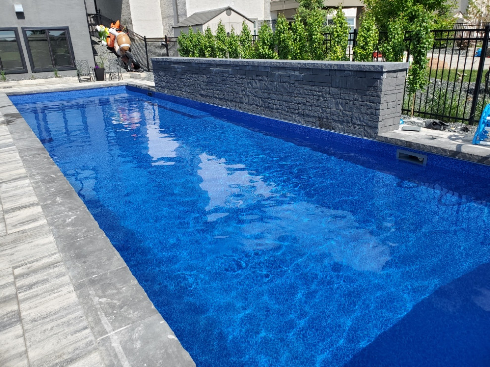 Стильный дизайн: прямоугольный бассейн среднего размера на заднем дворе в стиле модернизм с мощением клинкерной брусчаткой - последний тренд