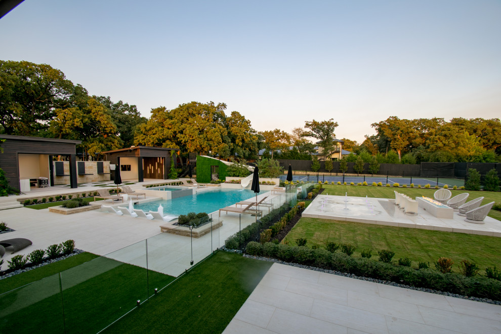 Ejemplo de piscina con tobogán alargada moderna grande a medida en patio trasero con suelo de baldosas