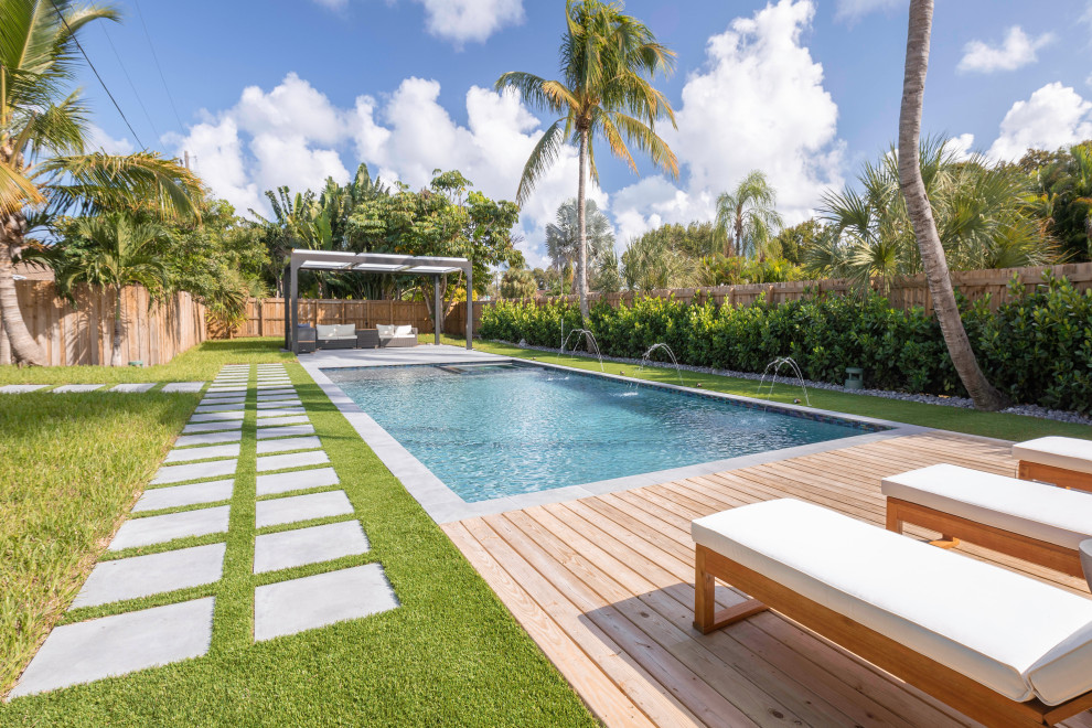 Foto de piscinas y jacuzzis alargados modernos de tamaño medio rectangulares en patio trasero con entablado