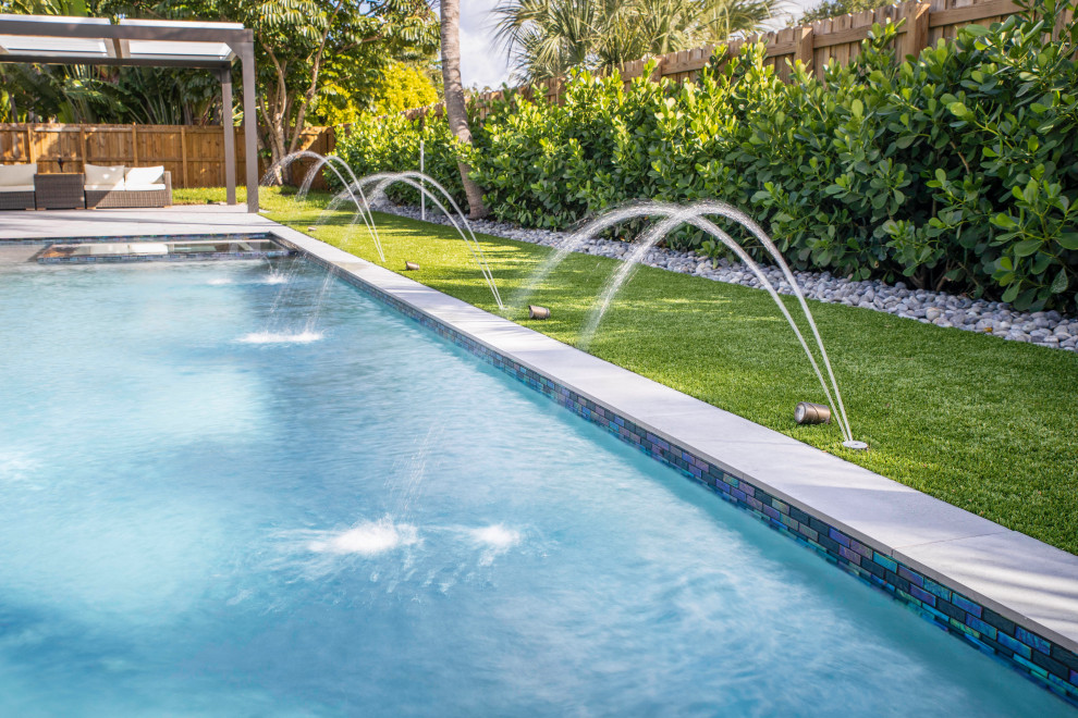 Ispirazione per una piscina monocorsia minimalista rettangolare di medie dimensioni e dietro casa con una vasca idromassaggio e pedane