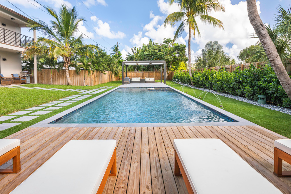 Exemple d'un couloir de nage arrière moderne de taille moyenne et rectangle avec un bain bouillonnant et une terrasse en bois.