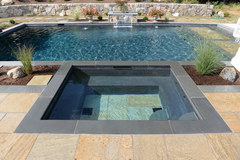 Aménagement d'une piscine arrière classique de taille moyenne et rectangle avec un bain bouillonnant et des pavés en pierre naturelle.