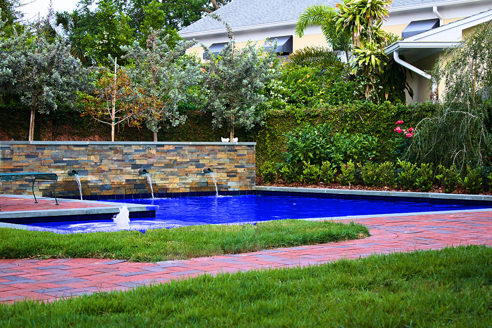 Immagine di una piscina naturale tradizionale personalizzata di medie dimensioni e dietro casa con fontane e pavimentazioni in mattoni
