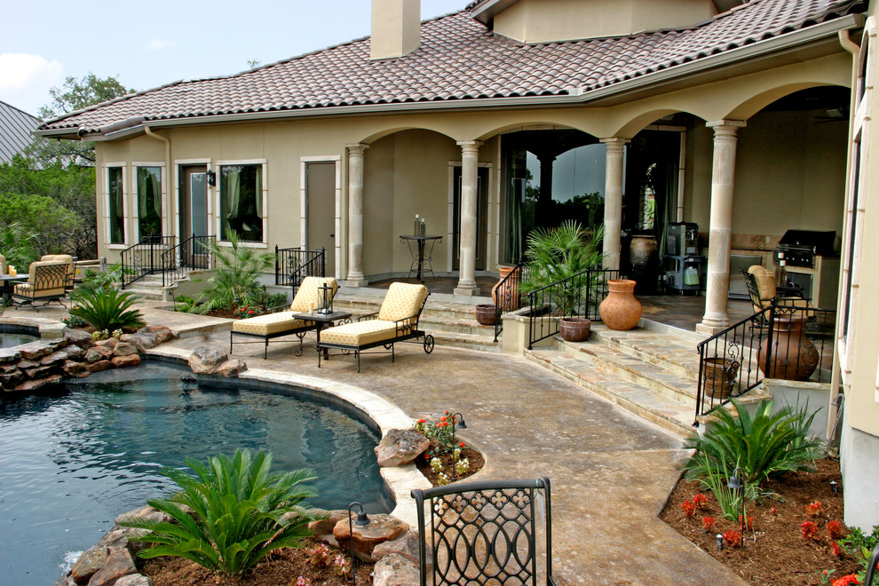 Design ideas for a large traditional back custom shaped infinity swimming pool in Austin with natural stone paving.
