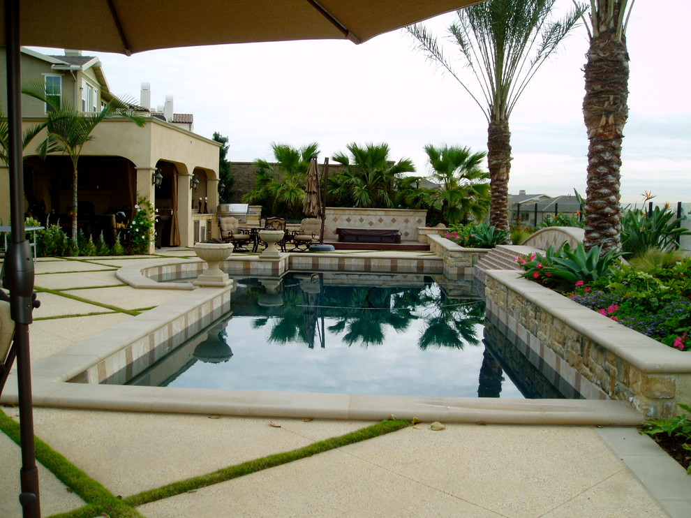 Foto de piscina natural mediterránea grande a medida en patio trasero con losas de hormigón