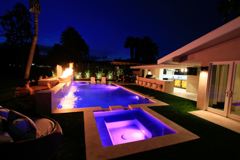 Immagine di una piscina naturale moderna rettangolare di medie dimensioni e dietro casa con una vasca idromassaggio e pavimentazioni in pietra naturale