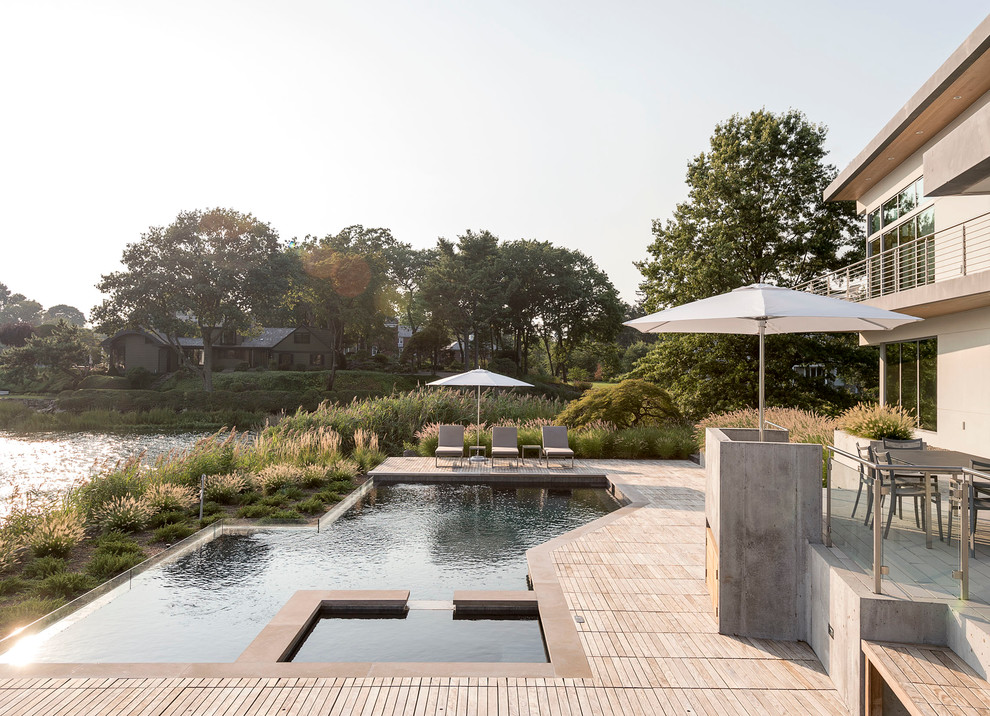 Idee per una piscina naturale moderna personalizzata dietro casa e di medie dimensioni con una vasca idromassaggio e pedane