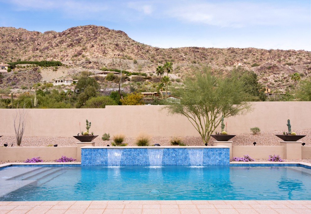 На фото: большой прямоугольный бассейн на заднем дворе в стиле фьюжн с покрытием из каменной брусчатки с