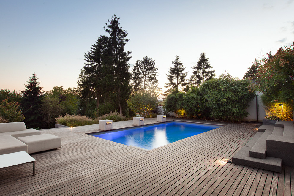 Diseño de piscina actual rectangular en patio trasero con entablado