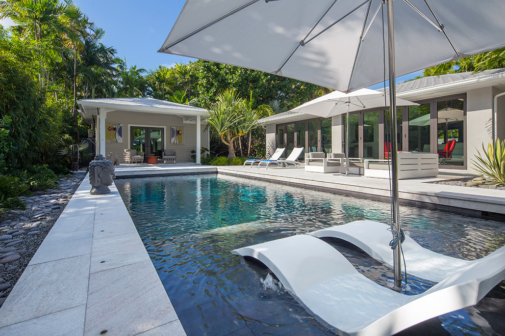 Pool - mid-sized tropical backyard pool idea in Miami