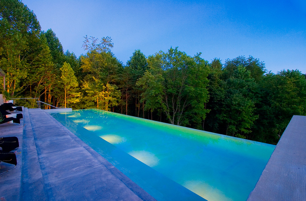 Diseño de casa de la piscina y piscina infinita contemporánea grande rectangular en patio trasero con losas de hormigón