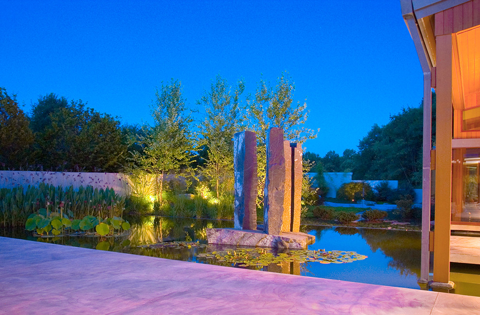 Modelo de piscina natural de estilo zen grande a medida en patio con adoquines de hormigón
