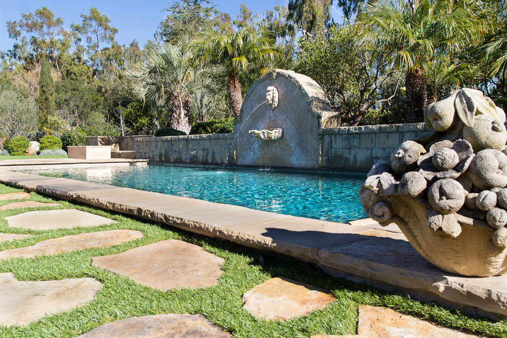 Diseño de piscina con fuente natural mediterránea de tamaño medio rectangular en patio trasero con adoquines de piedra natural
