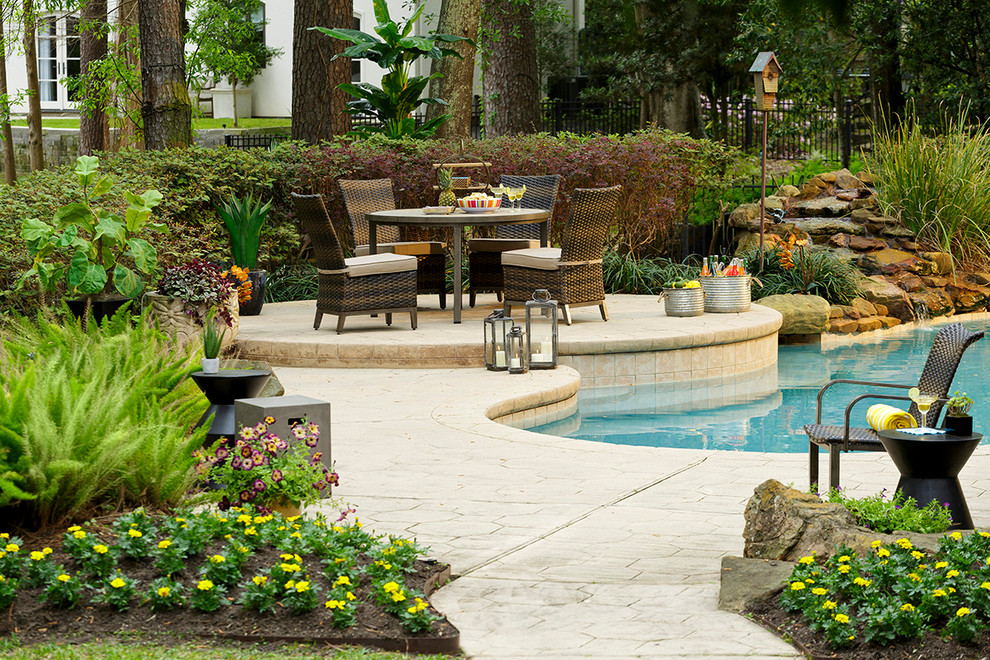 Trendy backyard stamped concrete and custom-shaped natural pool fountain photo in Houston