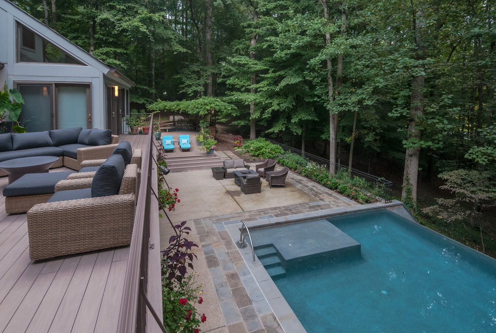 Foto de piscina infinita actual extra grande rectangular en patio trasero con adoquines de piedra natural