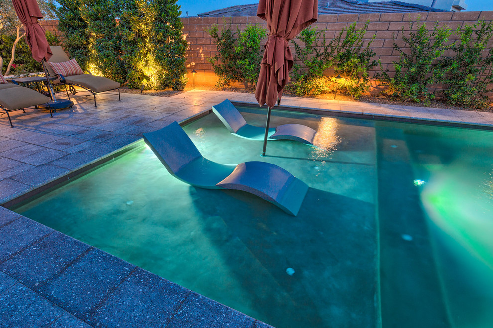 Ejemplo de piscinas y jacuzzis alargados actuales extra grandes rectangulares en patio trasero con adoquines de piedra natural