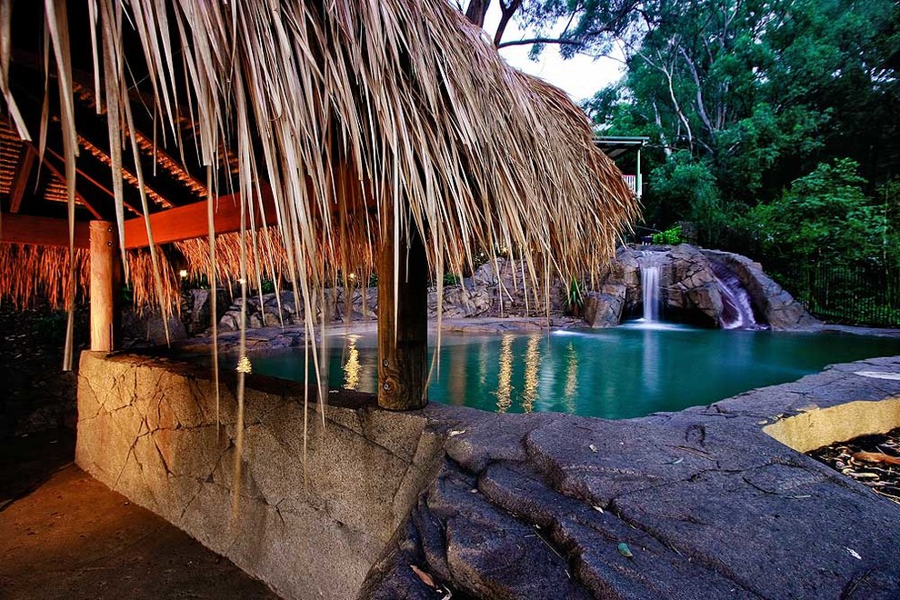 Foto di una piscina naturale tropicale personalizzata di medie dimensioni e davanti casa con un acquascivolo e cemento stampato