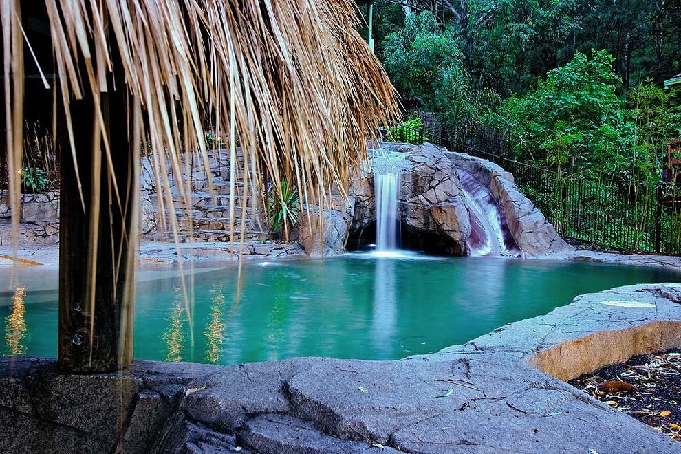 Esempio di una piscina naturale tropicale personalizzata di medie dimensioni e davanti casa con un acquascivolo e cemento stampato