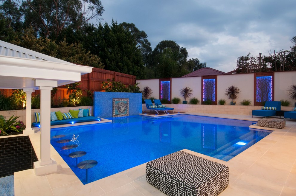 This is an example of a large classic back custom shaped lengths swimming pool in Melbourne with a water feature and natural stone paving.