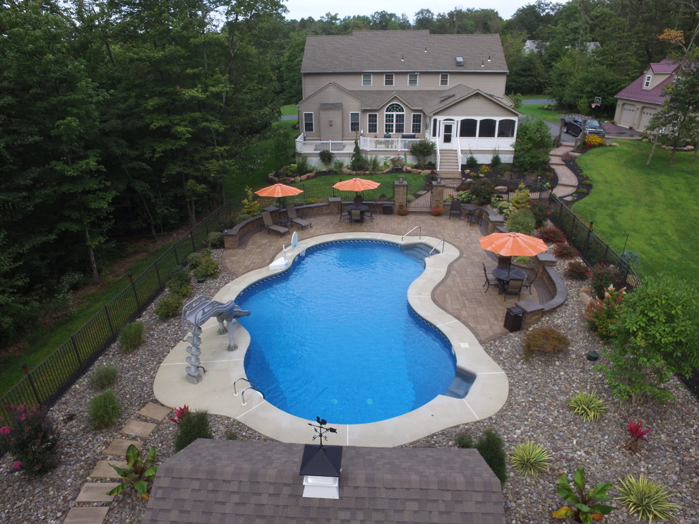 Design ideas for a large back custom shaped swimming pool in Philadelphia with concrete paving.