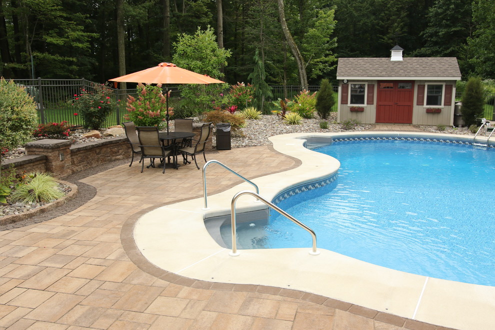 Esempio di un'ampia piscina a sfioro infinito classica a "C" dietro casa con un acquascivolo e pavimentazioni in mattoni
