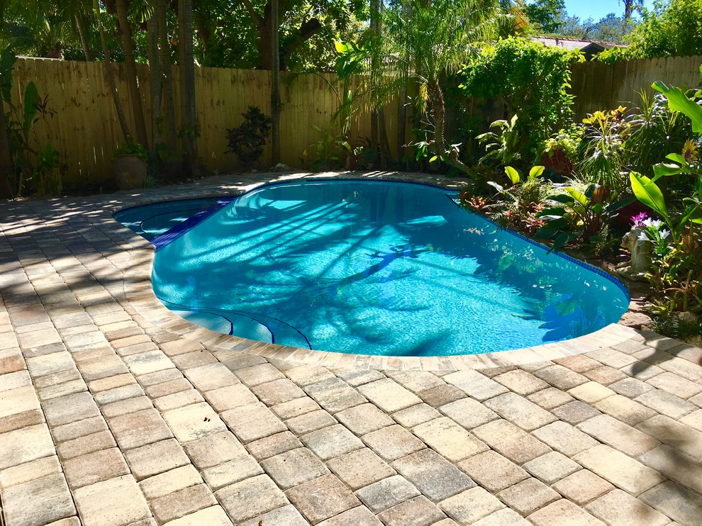 Immagine di una grande piscina naturale chic a "C" dietro casa con pavimentazioni in mattoni